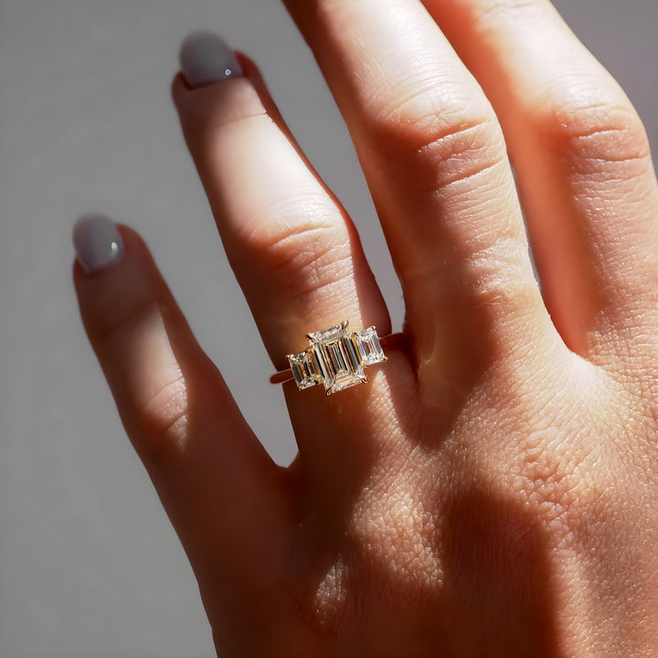 טבעת אירוסין שלוש אבנים 1.5 קראט יהלום אמרלד ואבני צד אמרלד