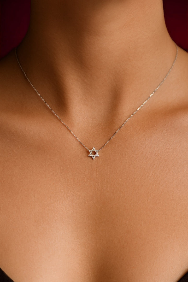 Star of David necklace on a person's neck against a neutral background